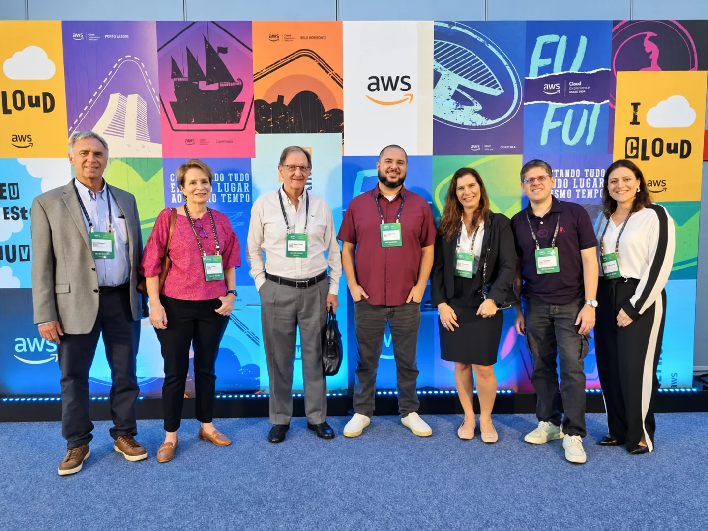 Equipe reunida diante do painel do evento AWS Cloud Experience.